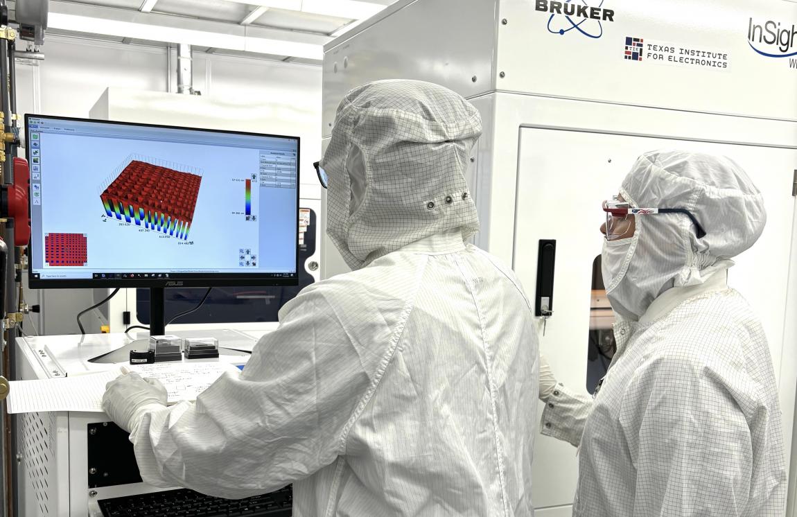 researchers in clean room suits at a computer