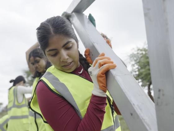 student holding a beam with other students as part of building project