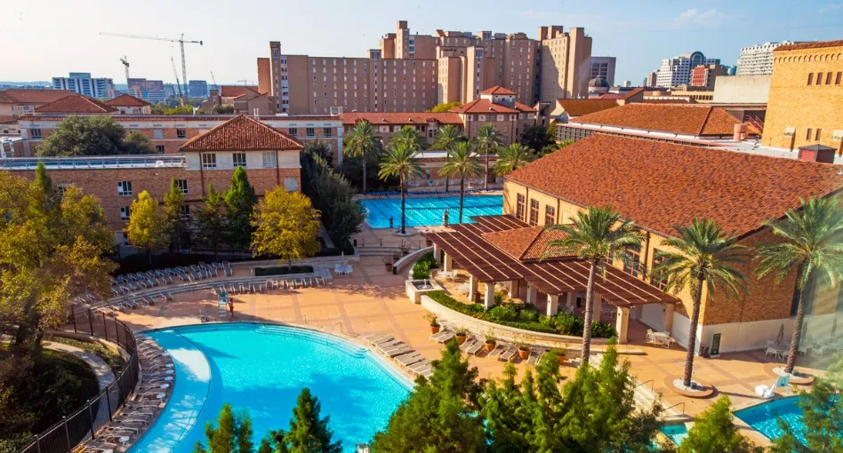 Show of Gregory Gym Aquatic Complex with red tile roofs and bright blue swimming pools during the day.