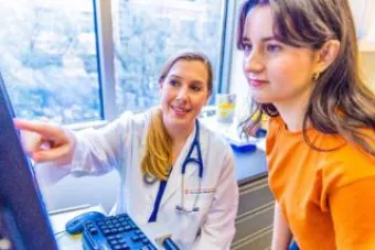  A doctor in white coat points to something on a monitor