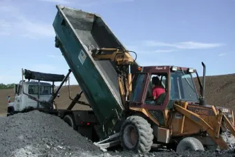 Dump truck and end loader by a pile of rare earth elements